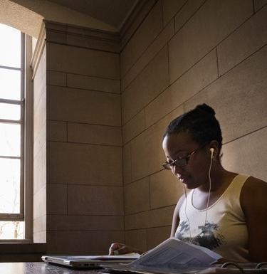 Student studying near a window with headphones in