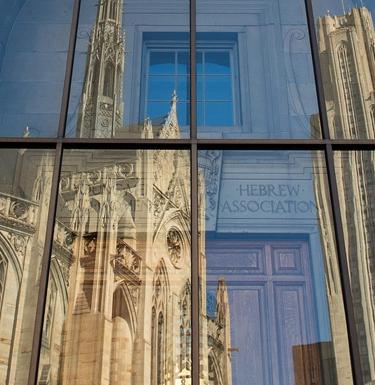 A gothic-style building reflected in the window of another building