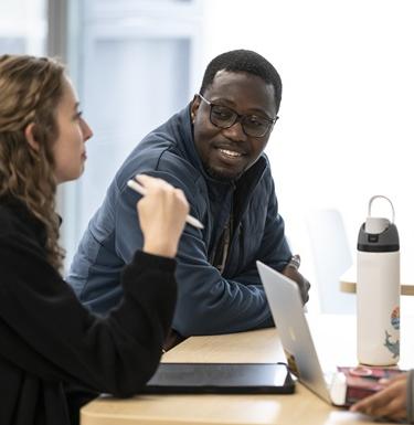 Two students sitting at a table talking