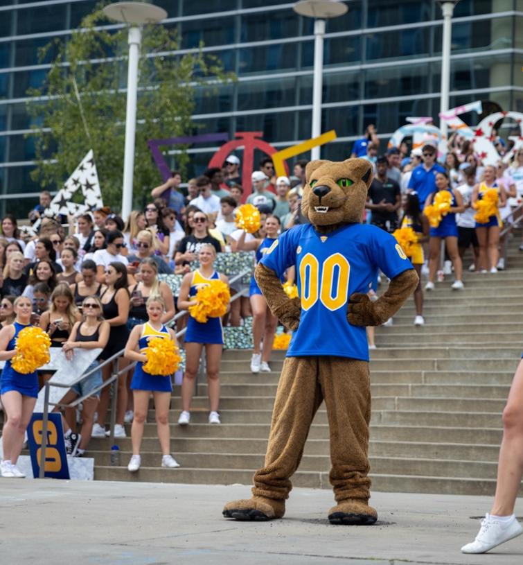 A crowd gathers on the stairs behind the Pitt Panther mascot and cheerleaders outside of the Peterson Events Center