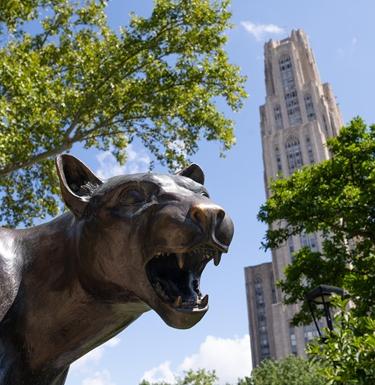 Closeup of the Pitt Panther statue with the Cathedral of Learning in the background